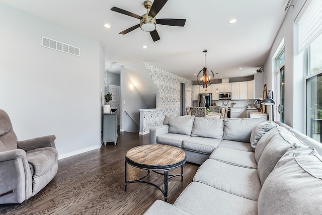 living room with visible vents, baseboards, dark wood-style floors, recessed lighting, and ceiling fan with notable chandelier