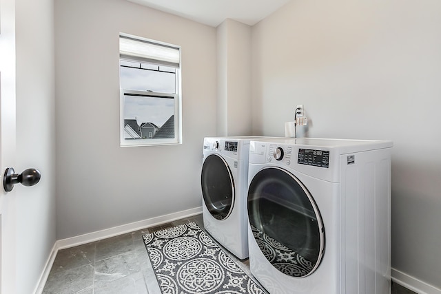 washroom featuring washing machine and clothes dryer, laundry area, and baseboards