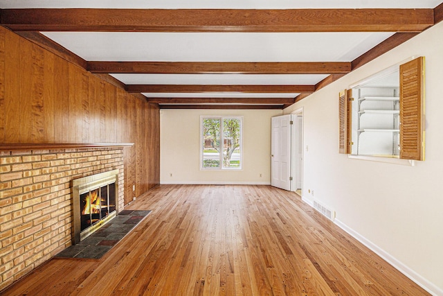 2038 S 7th St, Ann Arbor, MI 48103 - unfurnished living room featuring a fireplace, visible vents, beam ceiling, and hardwood / wood-style floors