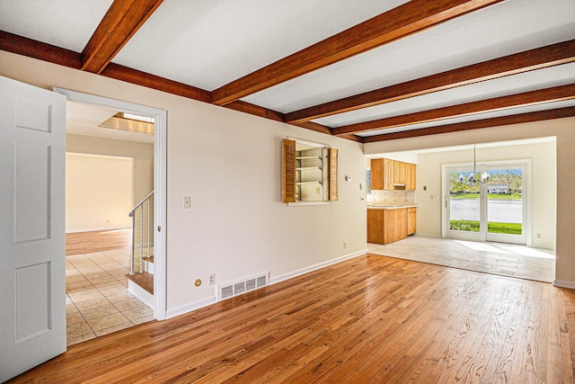 2038 S 7th St, Ann Arbor, MI 48103 - unfurnished living room featuring a notable chandelier, beam ceiling, light wood finished floors, visible vents, and stairway