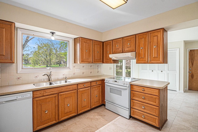 2038 S 7th St, Ann Arbor, MI 48103 - kitchen featuring brown cabinetry, decorative backsplash, white appliances, under cabinet range hood, and a sink