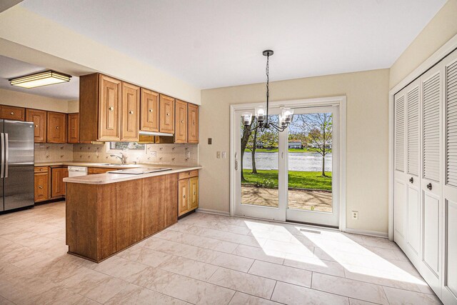 2038 S 7th St, Ann Arbor, MI 48103 - kitchen with stainless steel fridge, light countertops, a chandelier, brown cabinetry, and a peninsula