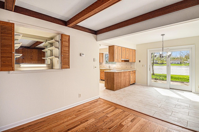 2038 S 7th St, Ann Arbor, MI 48103 - unfurnished living room featuring light wood-style floors, baseboards, beam ceiling, and an inviting chandelier