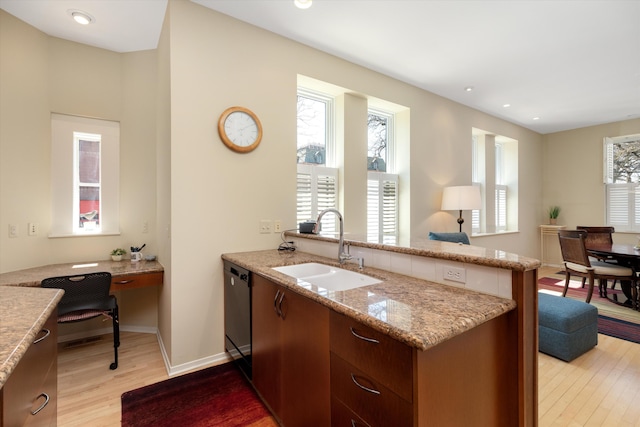 223 E Ann St Unit 1, Ann Arbor, MI 48104 - kitchen with a sink, light stone counters, light wood finished floors, a peninsula, and black dishwasher
