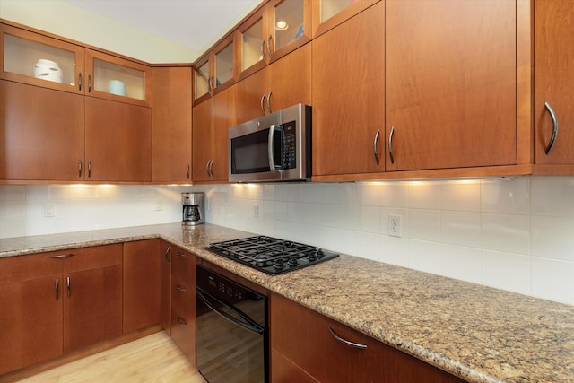 223 E Ann St Unit 1, Ann Arbor, MI 48104 - kitchen featuring light stone counters, light wood-style flooring, decorative backsplash, glass insert cabinets, and black appliances