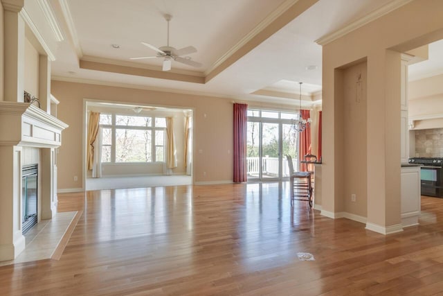 8660 Oakland Hills Cir, Portage, MI 49024 - unfurnished living room with light wood-type flooring, ceiling fan with notable chandelier, a tray ceiling, and a wealth of natural light