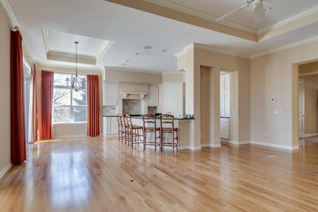 8660 Oakland Hills Cir, Portage, MI 49024 - living room featuring baseboards, light wood-style flooring, a raised ceiling, and ornamental molding
