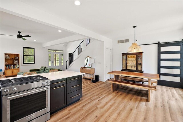 12950 Flynn Rd, Sawyer, MI 49125 - kitchen featuring stainless steel range with gas stovetop, open floor plan, a barn door, light wood finished floors, and light countertops