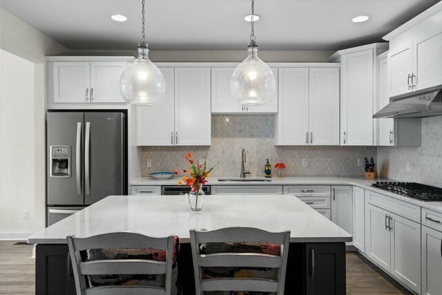 3100 Millbury Ln, Ann Arbor, MI 48105 - kitchen featuring stainless steel refrigerator with ice dispenser, gas stovetop, under cabinet range hood, dark wood finished floors, and decorative light fixtures