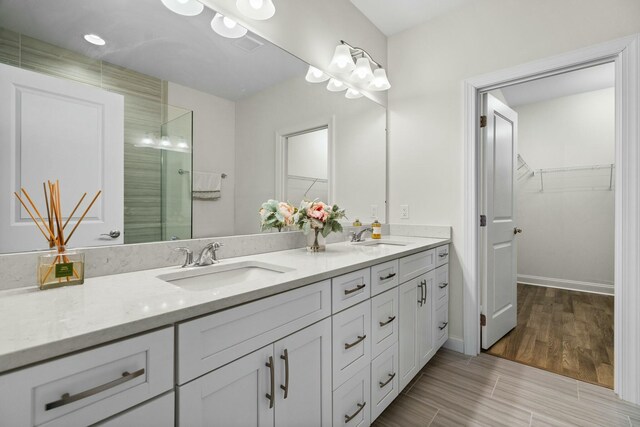 3100 Millbury Ln, Ann Arbor, MI 48105 - bathroom featuring double vanity, a walk in closet, a shower with door, and wood finished floors