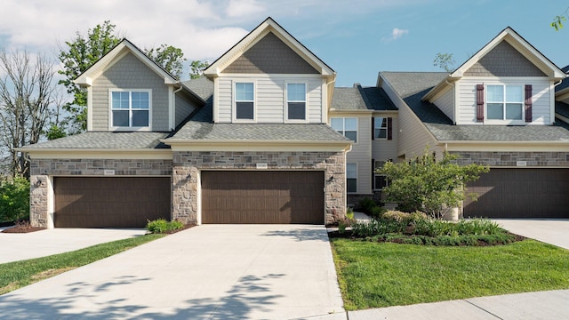 3100 Millbury Ln, Ann Arbor, MI 48105 - craftsman house featuring a garage, stone siding, driveway, roof with shingles, and a front yard