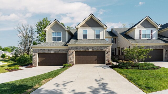 3100 Millbury Ln, Ann Arbor, MI 48105 - craftsman inspired home featuring an attached garage, stone siding, driveway, a front yard, and a shingled roof