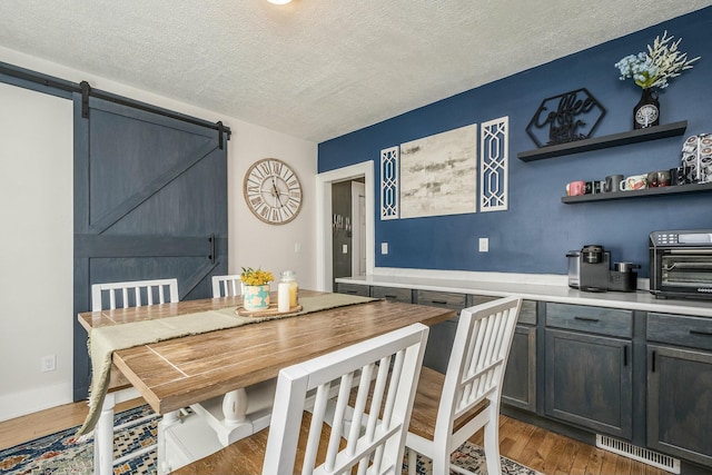 1146 Hall St SE, Grand Rapids, MI 49507 - dining room with a textured ceiling, a barn door, wood finished floors, and a toaster