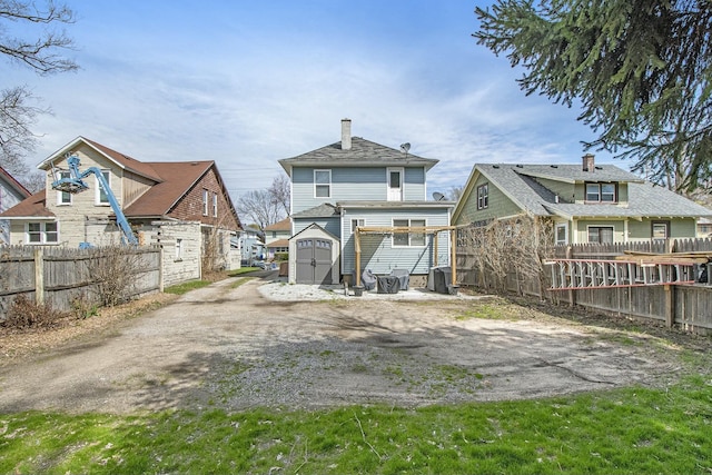 1146 Hall St SE, Grand Rapids, MI 49507 - rear view of house with a storage shed, fence, an outdoor structure, and dirt driveway