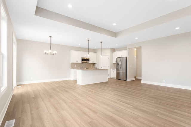 unfurnished living room with a notable chandelier, visible vents, a sink, and light wood-style floors