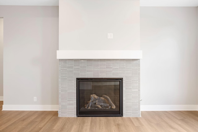 interior details with baseboards, wood finished floors, and a tile fireplace