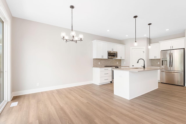 kitchen featuring appliances with stainless steel finishes, a sink, light countertops, decorative backsplash, and light wood-type flooring