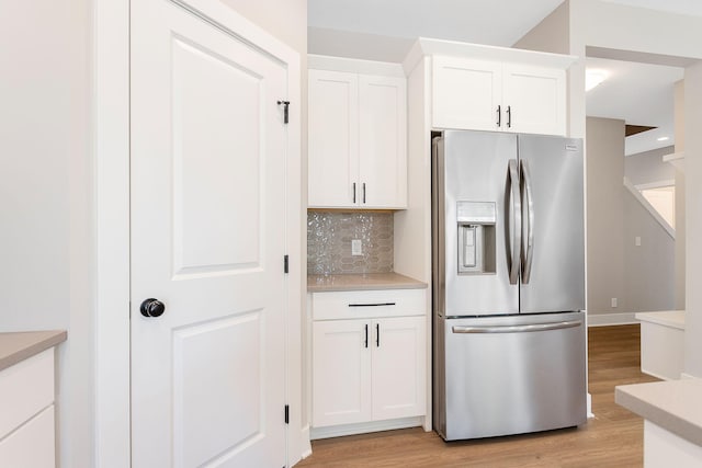 kitchen with backsplash, stainless steel refrigerator with ice dispenser, white cabinets, and light wood-style floors