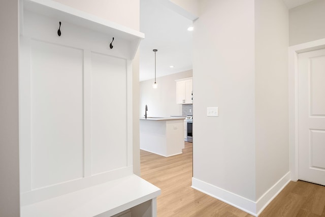 mudroom featuring a sink, baseboards, recessed lighting, and light wood-style flooring