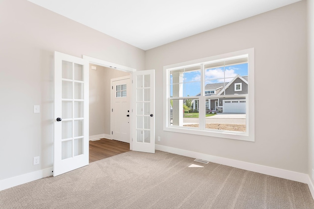 empty room with carpet floors, baseboards, visible vents, and french doors