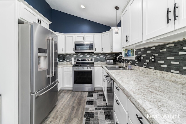 kitchen with a sink, appliances with stainless steel finishes, white cabinetry, and lofted ceiling