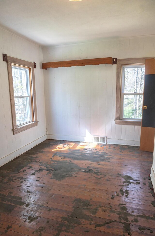 15232 Three Oaks Rd, Three Oaks, MI 49128 - empty room with wooden walls, visible vents, a healthy amount of sunlight, and dark wood-type flooring