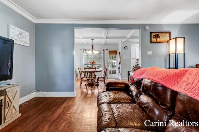 living area featuring ornamental molding, wood finished floors, baseboards, a chandelier, and coffered ceiling
