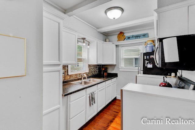 kitchen featuring a sink, backsplash, beam ceiling, and white cabinets