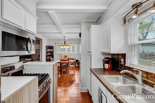 kitchen featuring an inviting chandelier, wood finished floors, beam ceiling, a sink, and stainless steel appliances