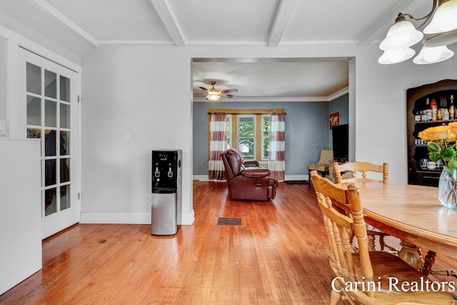 dining space featuring ceiling fan with notable chandelier, baseboards, wood finished floors, beamed ceiling, and visible vents