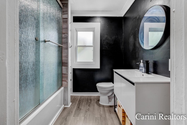 bathroom with vanity, toilet, combined bath / shower with glass door, wood finished floors, and ornamental molding