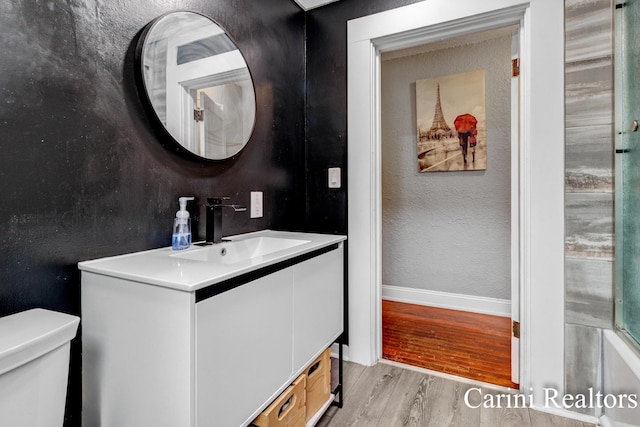 bathroom with baseboards, vanity, toilet, and wood finished floors