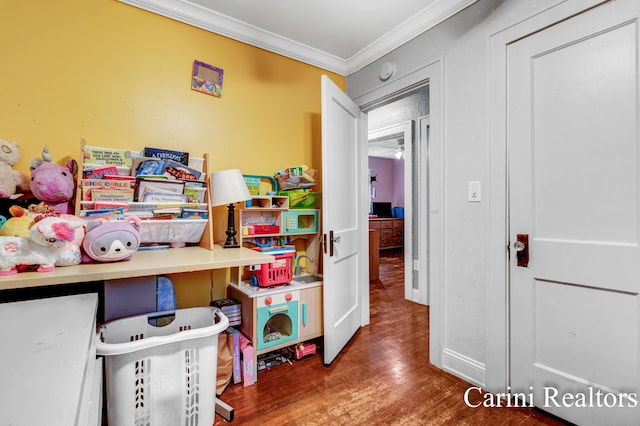 recreation room featuring ornamental molding and wood finished floors