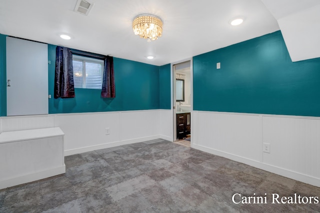 spare room featuring an inviting chandelier, wainscoting, and visible vents