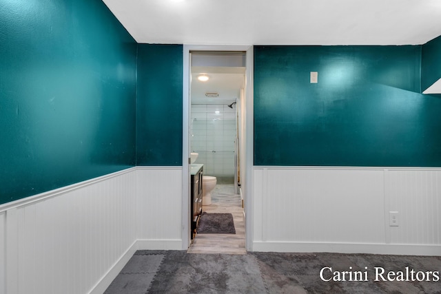 bathroom featuring a wainscoted wall, a stall shower, toilet, and wood finished floors