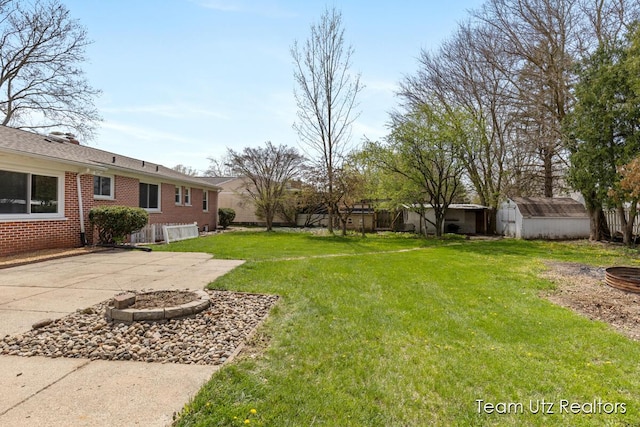 view of yard with a fire pit, fence, a shed, a patio area, and an outbuilding