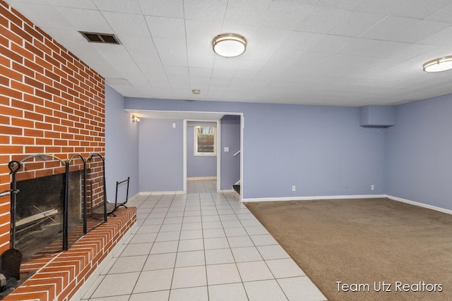 basement featuring visible vents, carpet, baseboards, and a brick fireplace