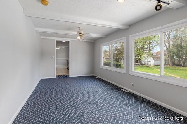 empty room with visible vents, baseboards, and beamed ceiling