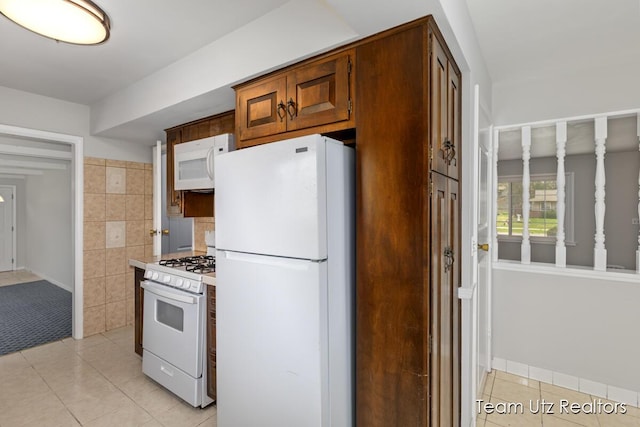 kitchen with light countertops, brown cabinetry, white appliances, and light tile patterned flooring