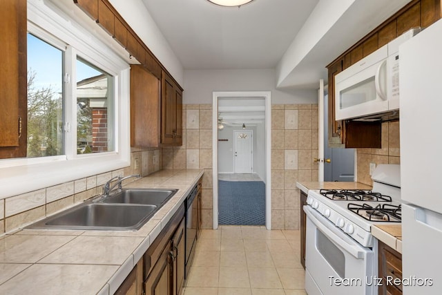 kitchen featuring a sink, plenty of natural light, white appliances, and light tile patterned flooring