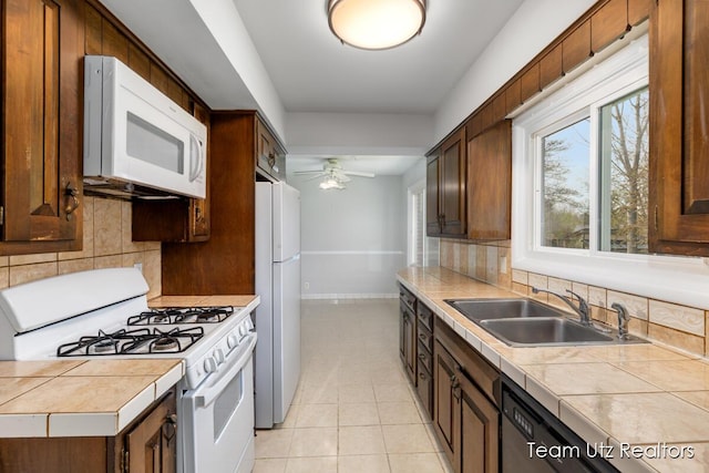 kitchen featuring a sink, light tile patterned flooring, white appliances, and tasteful backsplash
