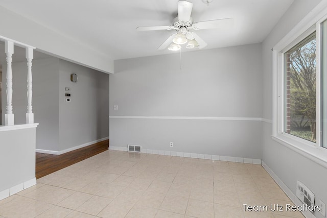 spare room featuring a healthy amount of sunlight, baseboards, ceiling fan, and visible vents
