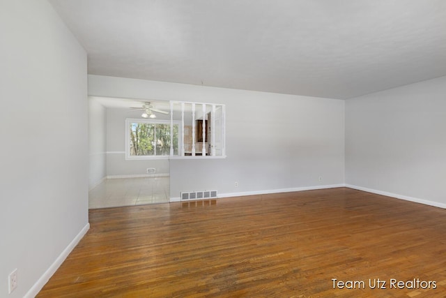 unfurnished room with baseboards, ceiling fan, wood finished floors, and visible vents