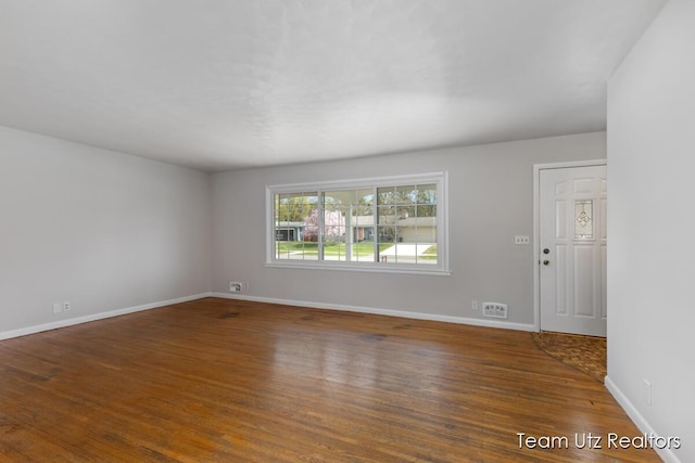 spare room with baseboards and wood finished floors