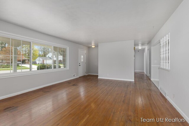 unfurnished living room with baseboards, wood-type flooring, and visible vents