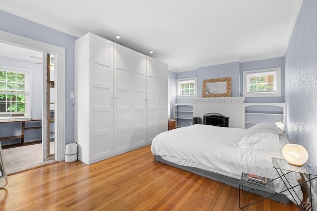 1021 Roseland Ave, Kalamazoo, MI 49001 - bedroom with light wood-type flooring, ornamental molding, a brick fireplace, a closet, and a textured wall