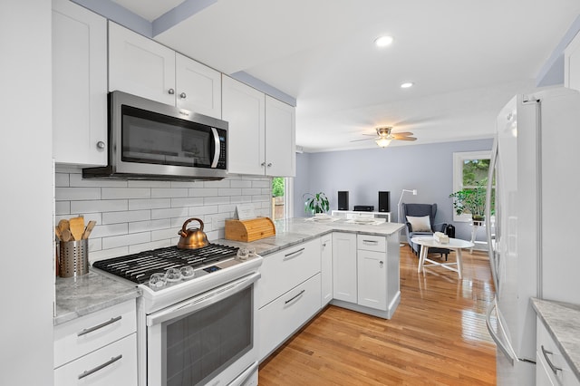 1021 Roseland Ave, Kalamazoo, MI 49001 - kitchen with freestanding refrigerator, stainless steel microwave, white gas range, light wood finished floors, and white cabinetry