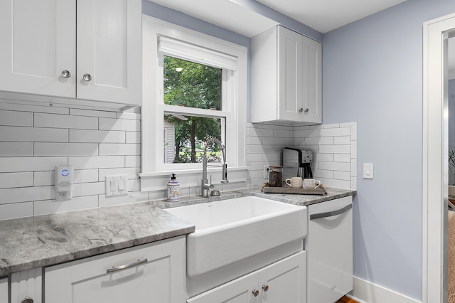 1021 Roseland Ave, Kalamazoo, MI 49001 - kitchen featuring white dishwasher, backsplash, white cabinets, and light stone counters