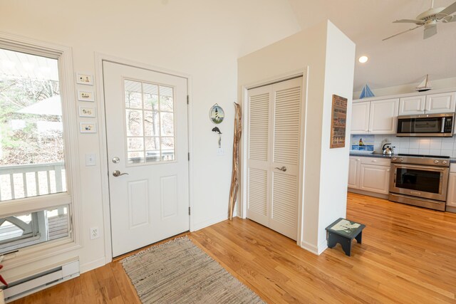 14 N Lighthouse Dr, Mears, MI 49436 - entrance foyer with a ceiling fan, baseboards, a baseboard radiator, light wood finished floors, and vaulted ceiling