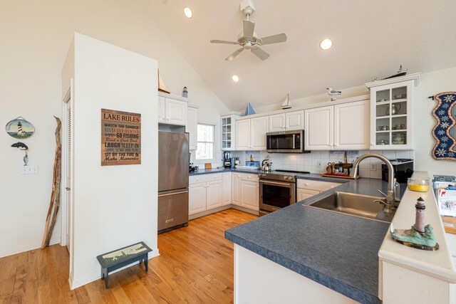 14 N Lighthouse Dr, Mears, MI 49436 - kitchen with white cabinets, dark countertops, appliances with stainless steel finishes, a sink, and decorative backsplash